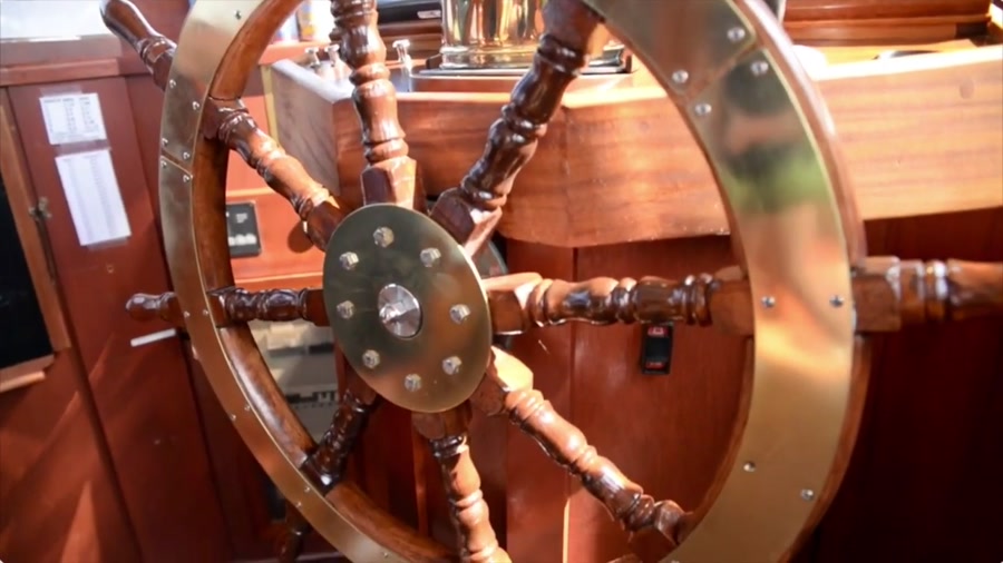 The restored ship's wheel — brass and hand-finished hardwood in the wheelhouse